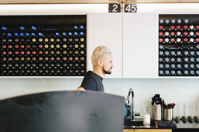 A man in profile standing by a sink in a hair salon.