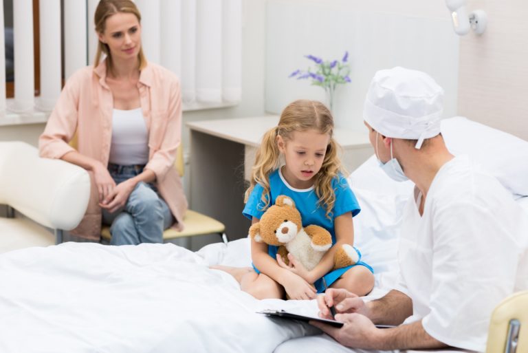 doctor talking with kid and sitting on hospital bed