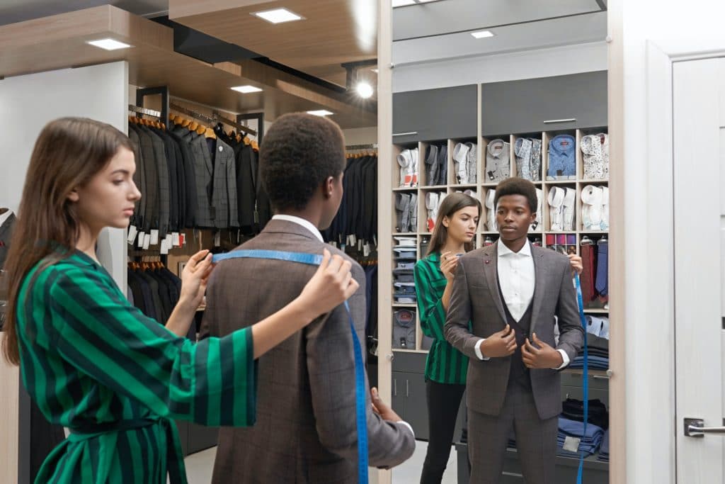 Client in shop in elegant suit looking at mirror