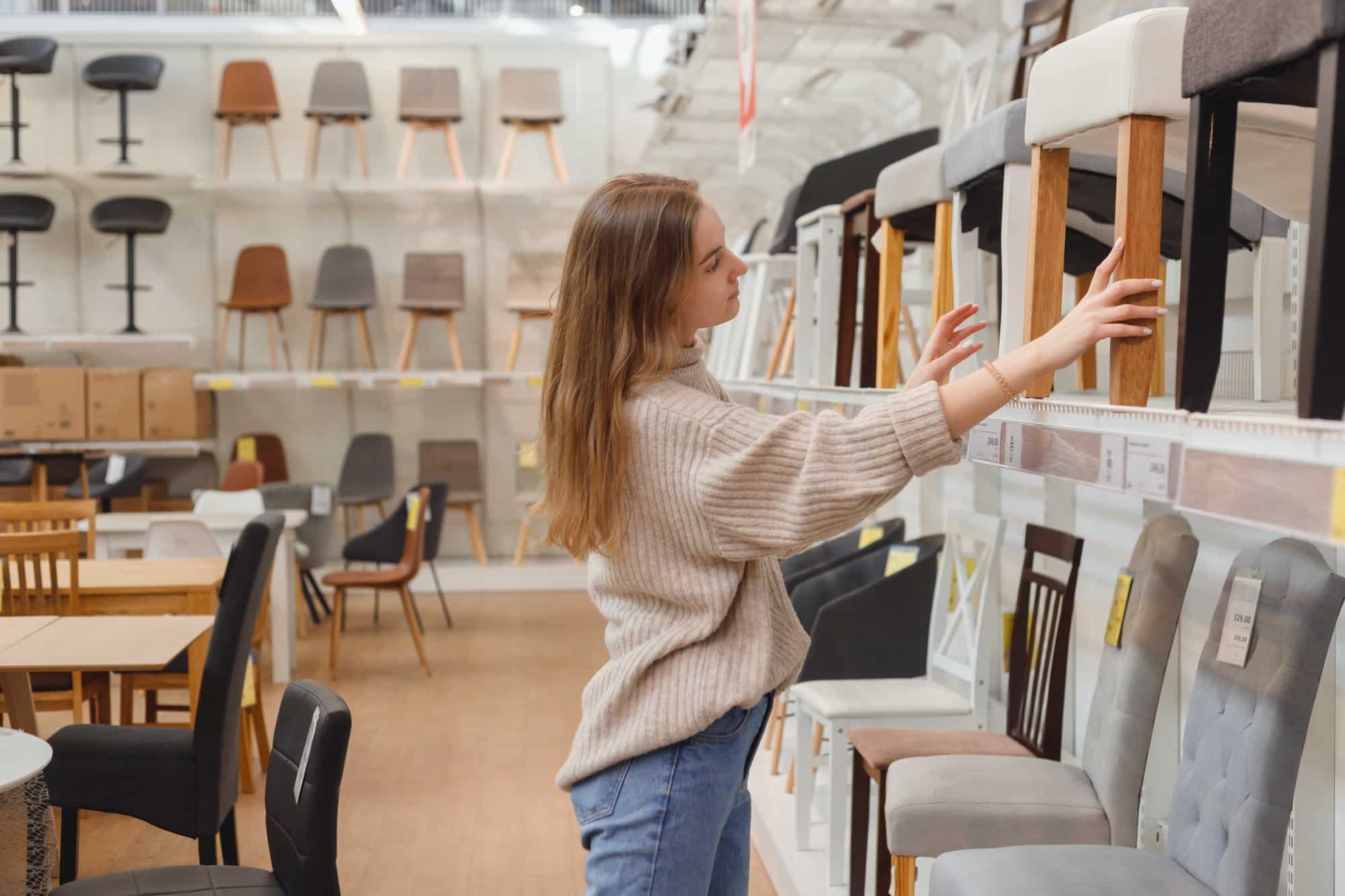 Young caucasian woman chooses furniture for her apartment in furniture store