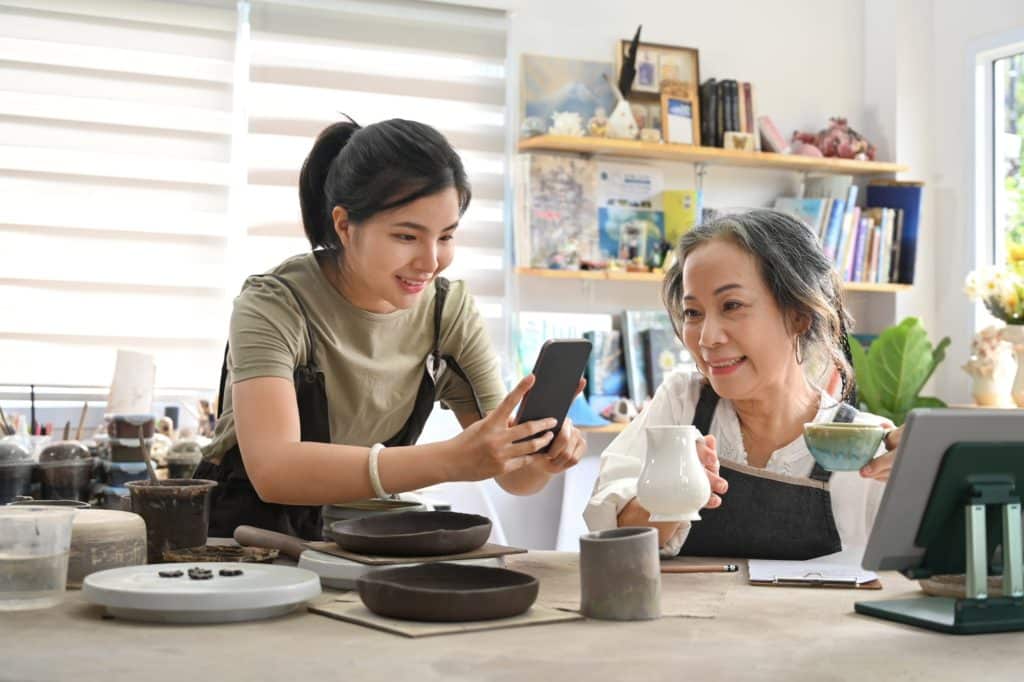 Handicraft pottery shop owners taking photo of product for upload to website online shop.